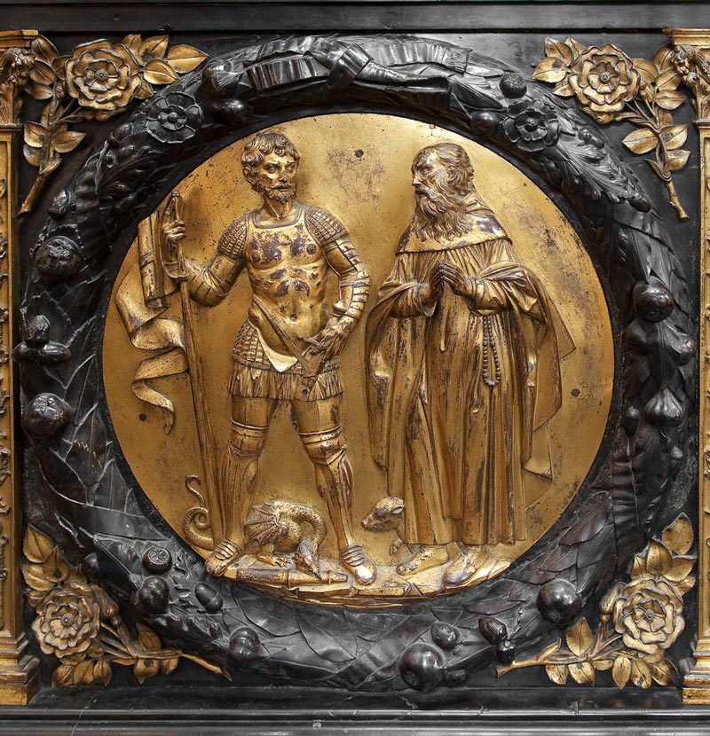 Bronze medallion depicting St George, in armour with a slain dragon at his feet and St Anthony, hands in prayer on tomb of Henry VII