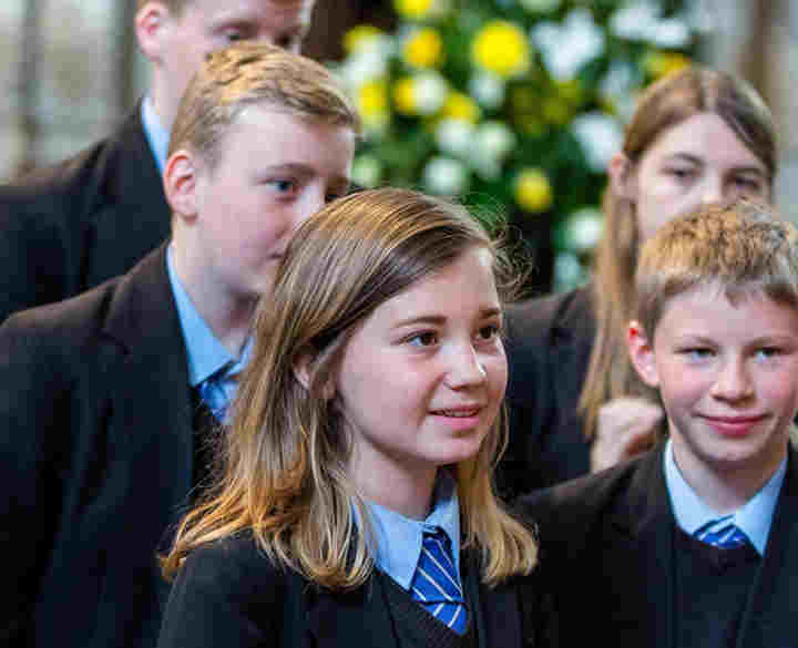A group of secondary school students listen to a guide during a tour of Westminster Abbey