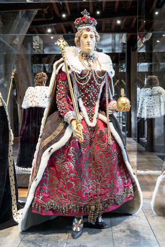 Wax effigy of Elizabeth I wearing a crown, red brocaded dress, fur-trimmed cloak and crown