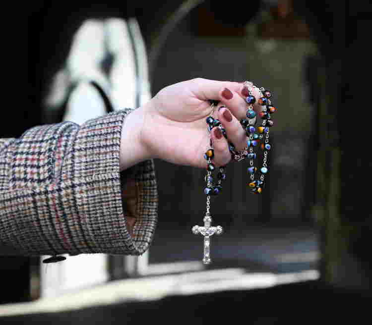 Rosary being held in a hand in front of a door at Westminster Abbey