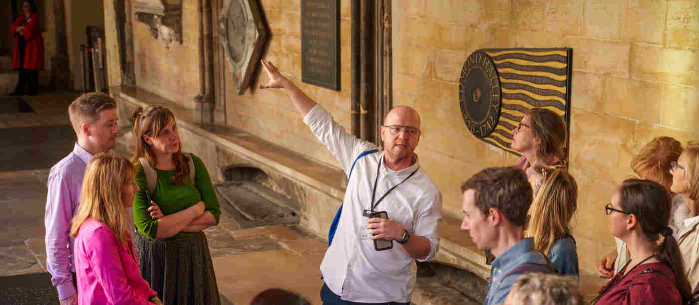 Photograph of adult leading a tour group in the cloisters of Westminster Abbey