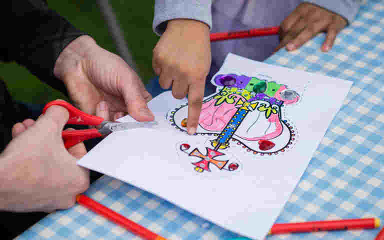 Photograph of an adult and a child creating a crown using the template provided by Westminster Abbey, representing the coronation crown template
