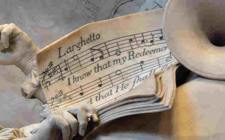 Photograph of memorial in Westminster Abbey in which a musical score is held by a stone hand