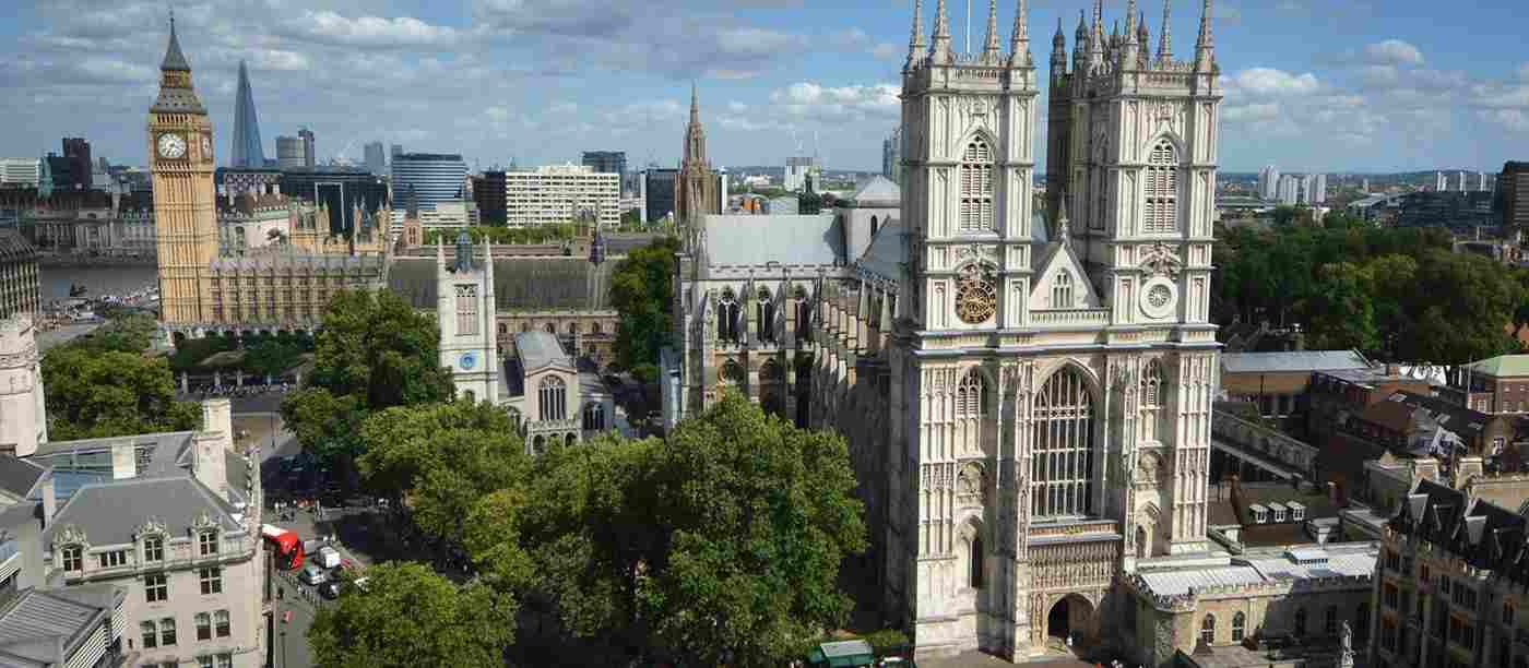 The West Front of Westminster Abbey on a sunny day. Big Ben can be seen in the background.