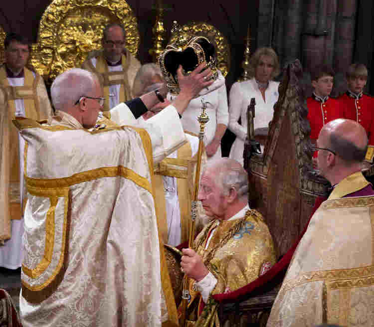 Photograph showing the moment of crowning of HM King Charles III at his coronation who is sitting on the Coronation Chair.