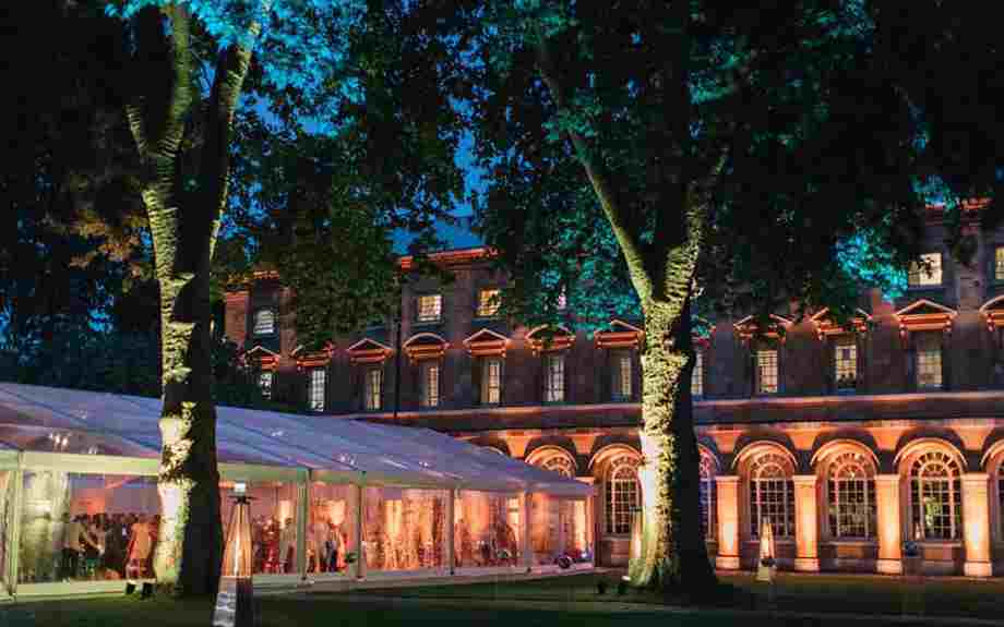 A glass marquee in Westminster Abbey's College Garden at night, with the garden lit up