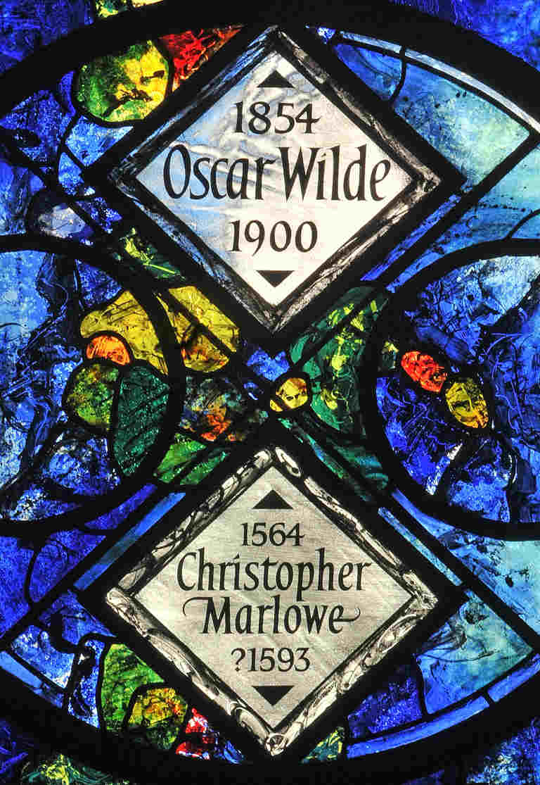 Colourful stained glass windows within which are white glass panels to Oscar Wilde and Christopher Marlowe