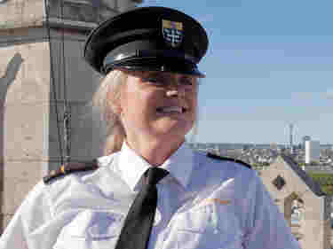 Photograph of smiling female security beadle wearing uniform, looking at from the top of the flag tower at Westminster Abbey
