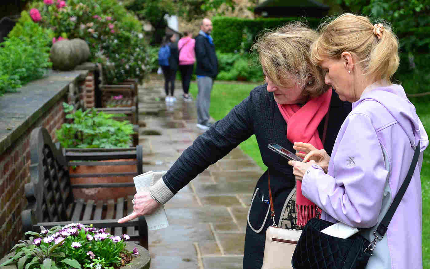 Photograph of two members of the public talking and pointing at flowers in College Garden at Westminster Abbey