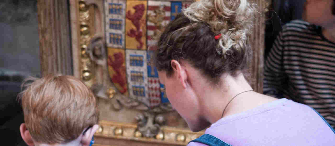 Photograph of two girls holding brightly coloured painted shields in the garden of Westminster Abbey