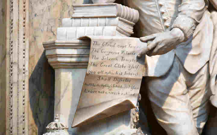 Photograph of memorial statue to William Shakespeare with an open scroll containing words