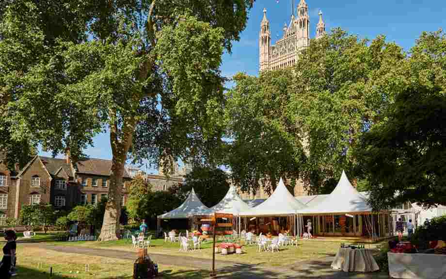 A glass marquee in Westminster Abbey's College Garden with the Victoria Tower behind