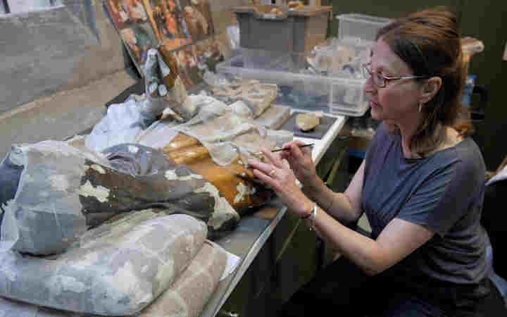 Photograph of female conservator inspecting materials within the conservation studio at Westminster Abbey
