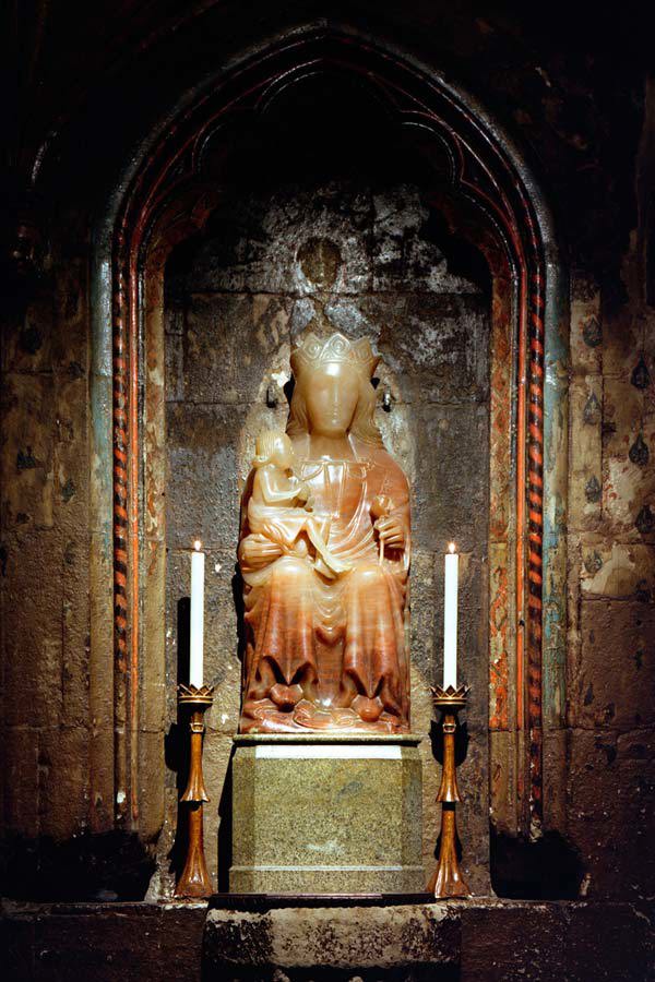 Statue of Our Lady of Pew on a stone altar with a small candle on each side
