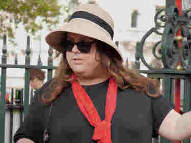 Photograph of women wearing a marshal uniform and sunhat welcoming visitors to Westminster Abbey