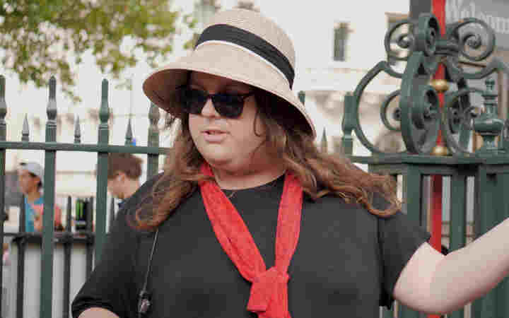Photograph of women wearing a marshal uniform and sunhat welcoming visitors to Westminster Abbey