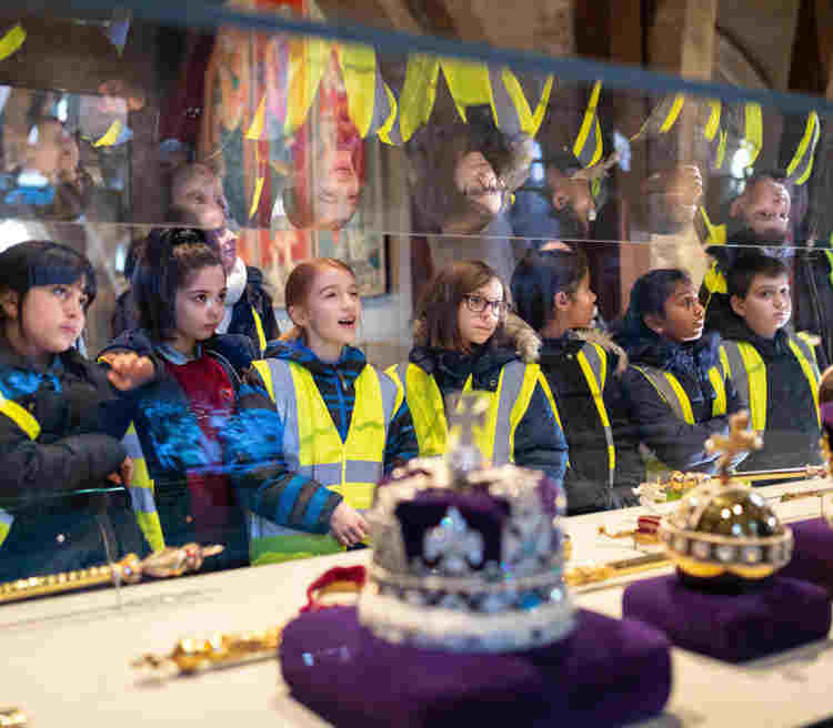 Photograph of children wearing high vis jackets looking at the coronation regalia exhibition within Westminster Abbey