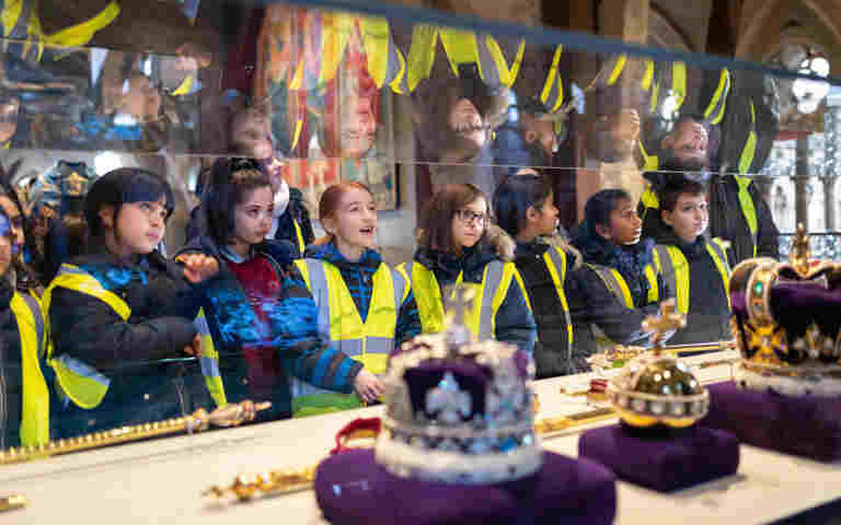 Photograph of children wearing high vis jackets looking at the coronation regalia exhibition within Westminster Abbey