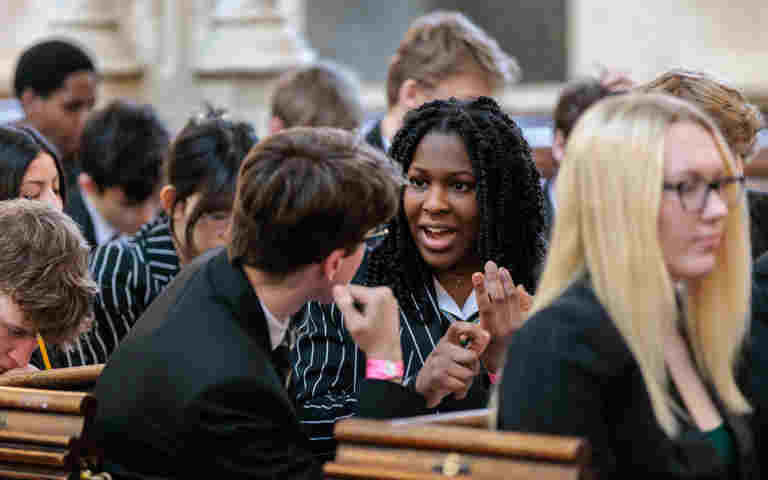 Photograph of sixth form students talking, sitting in pews within St Margaret's Church Westminster Abbey as part of a Question Time event