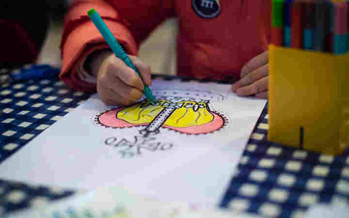 Photograph of crown colouring in sheet with a child's hand holding a pen and colouring in