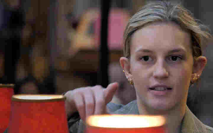 Photograph of a woman looking and pointing, with quire lamps in front of her, within Westminster Abbey