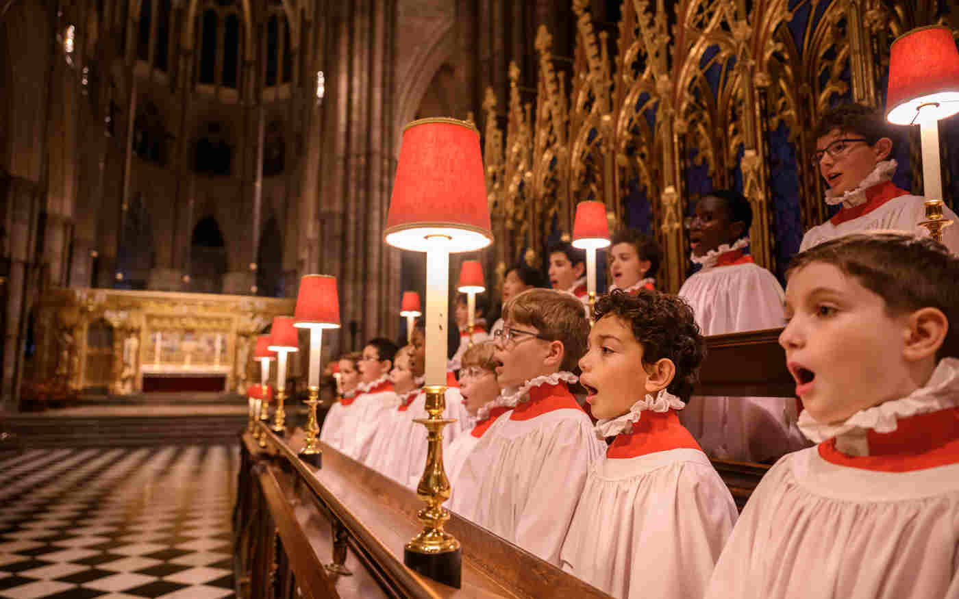 Choir boys singing with the high altar of westminster abbey in the background
