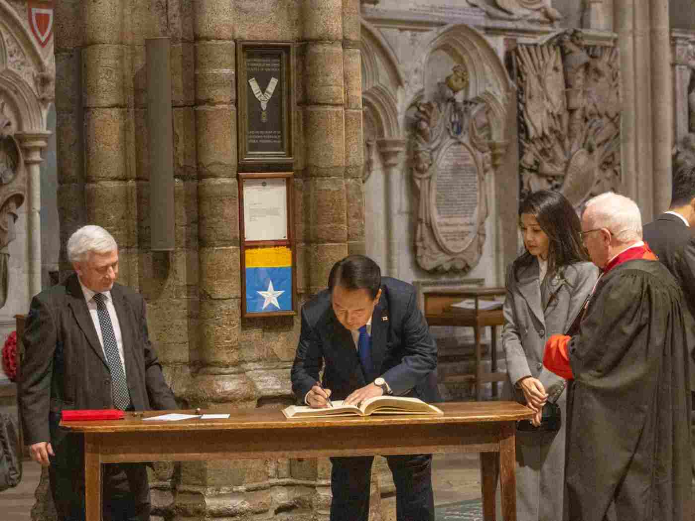 The President of the Korea Republic signing a book. His wife, The Dean and another man watch