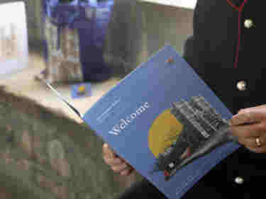Close-up photograph of a Westminster Abbey Association leaflet, being held by a person sitting within the Cloisters of Westminster Abbey