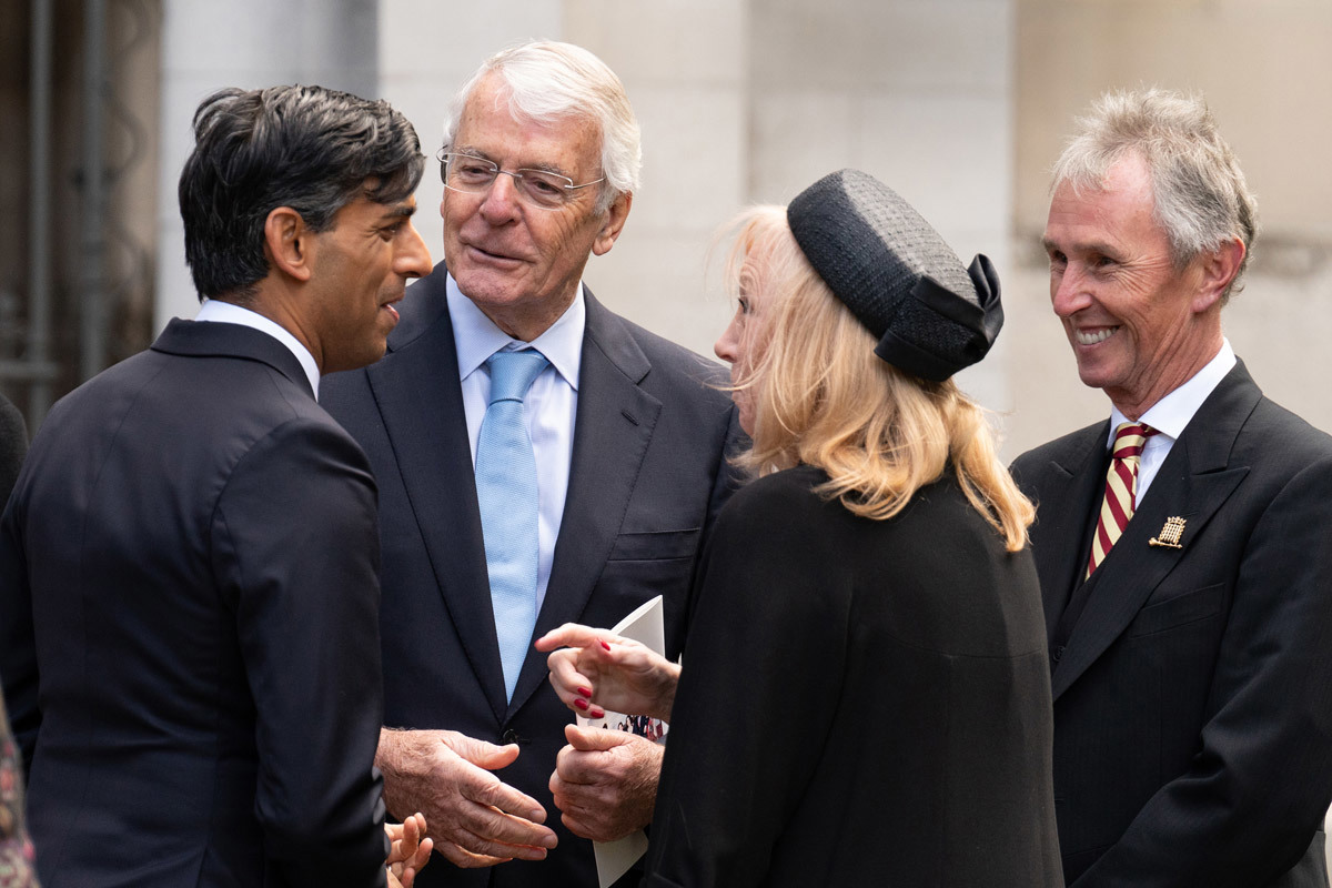 Prime Minister Rishi Sunak, former Prime Minister John Major and two other people dressed in black