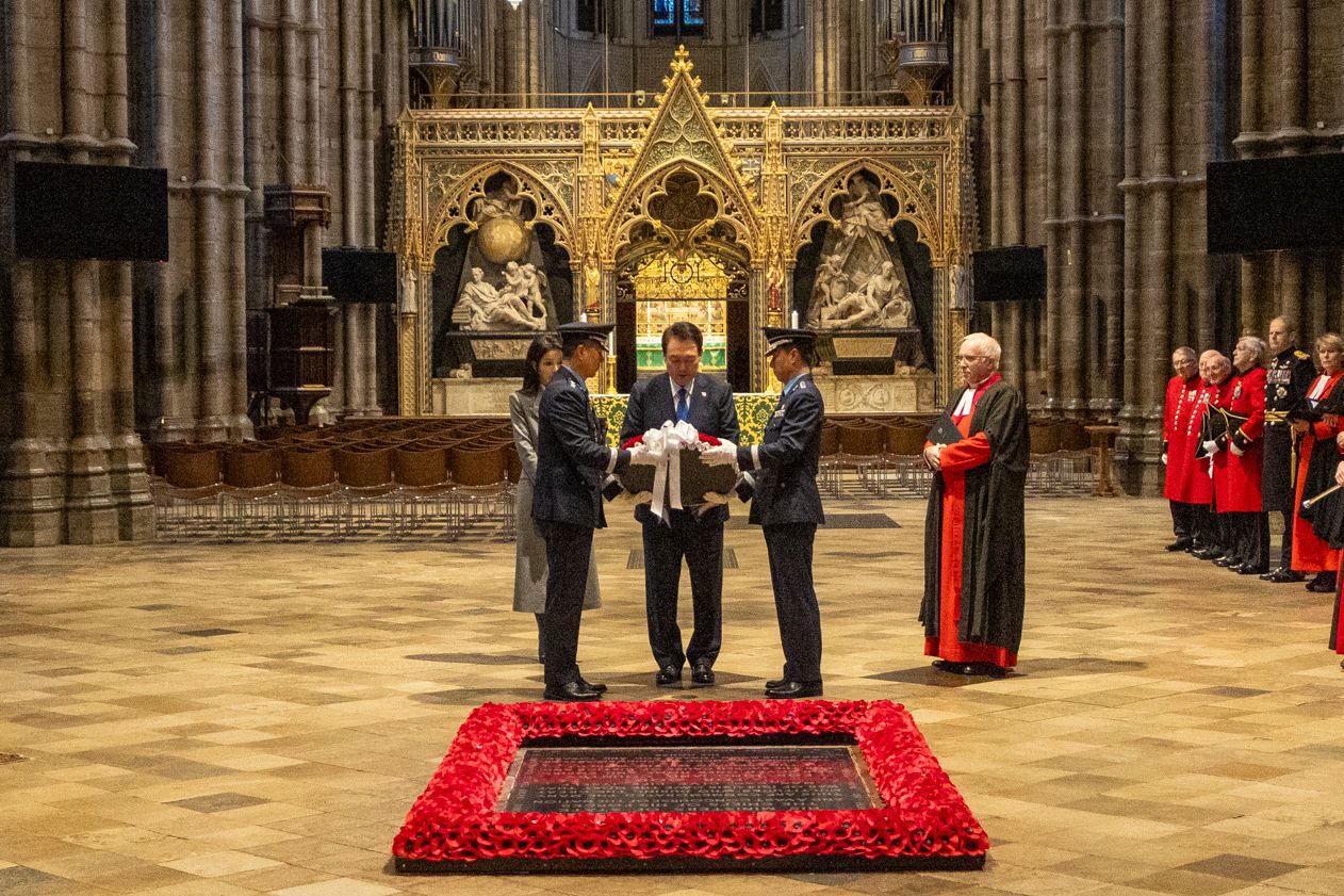 The president of the Korea Republic, flanked by two soldiers, holds a wreath