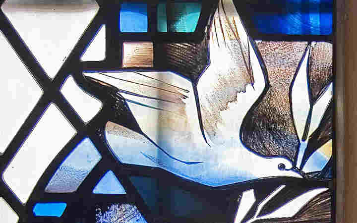 Close-up photograph of a dove, representing the Holy Spirit, within a stained-glass window in Westminster Abbey