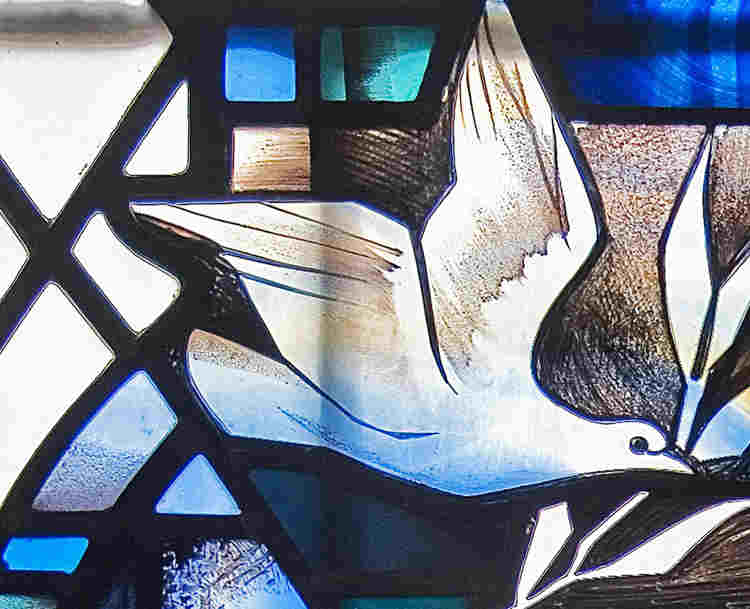 Close-up photograph of a dove, representing the Holy Spirit, within a stained-glass window in Westminster Abbey