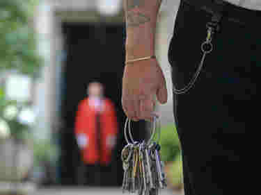 Photograph of member of security staff walking and holding a large number of keys at Westminster Abbey