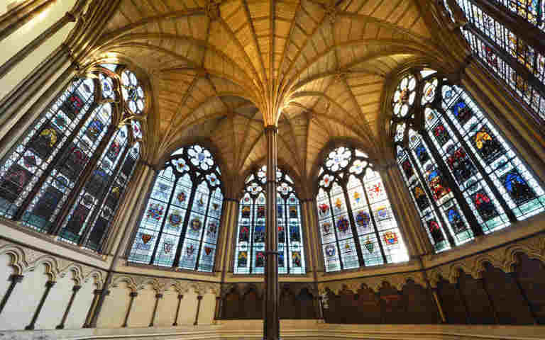Photograph of Chapter House, showing seating, middle column and stained-glass windows