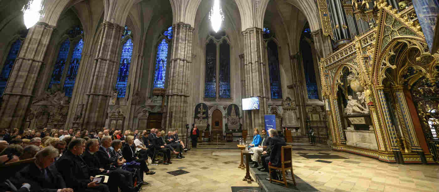 Photograph from the side of a panel discussion with the audience listening within the nave of Westminster Abbey