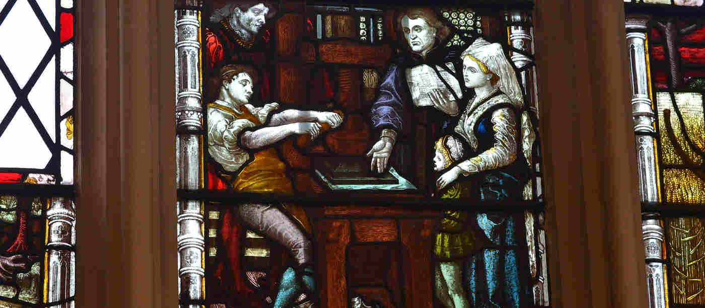 Photograph of the stained-glass window commemorating William Caxton and the printing press within St Margaret's Church, nextdoor to Westminster Abbey.
