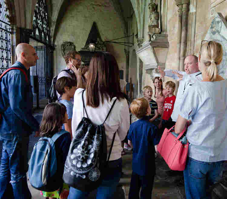 Photograph of the backs of young people and adults listening to a facilitator, representing home educated groups at Westminster Abbey