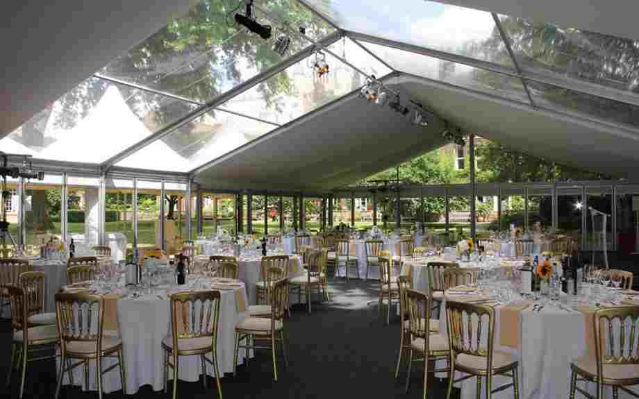 Tables and chairs arranged for dinner in a glass marquee in Westminster Abbey's College Garden