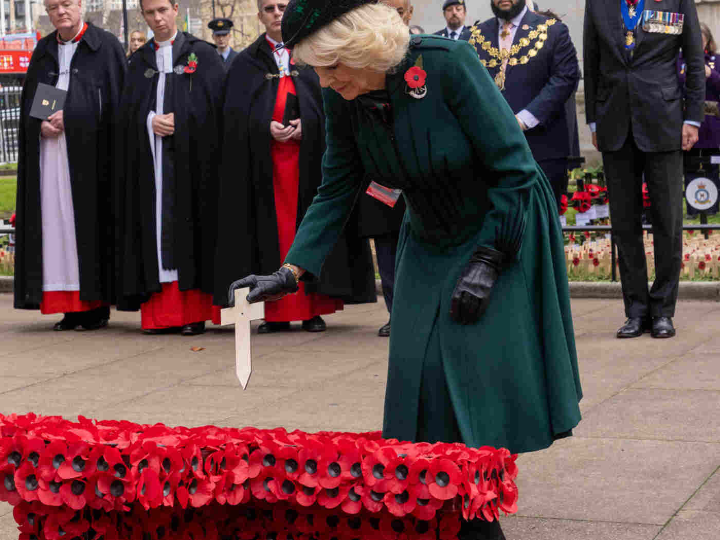 The Queen Consort lays a cross of remembrance on a larger cross decorated with poppies.