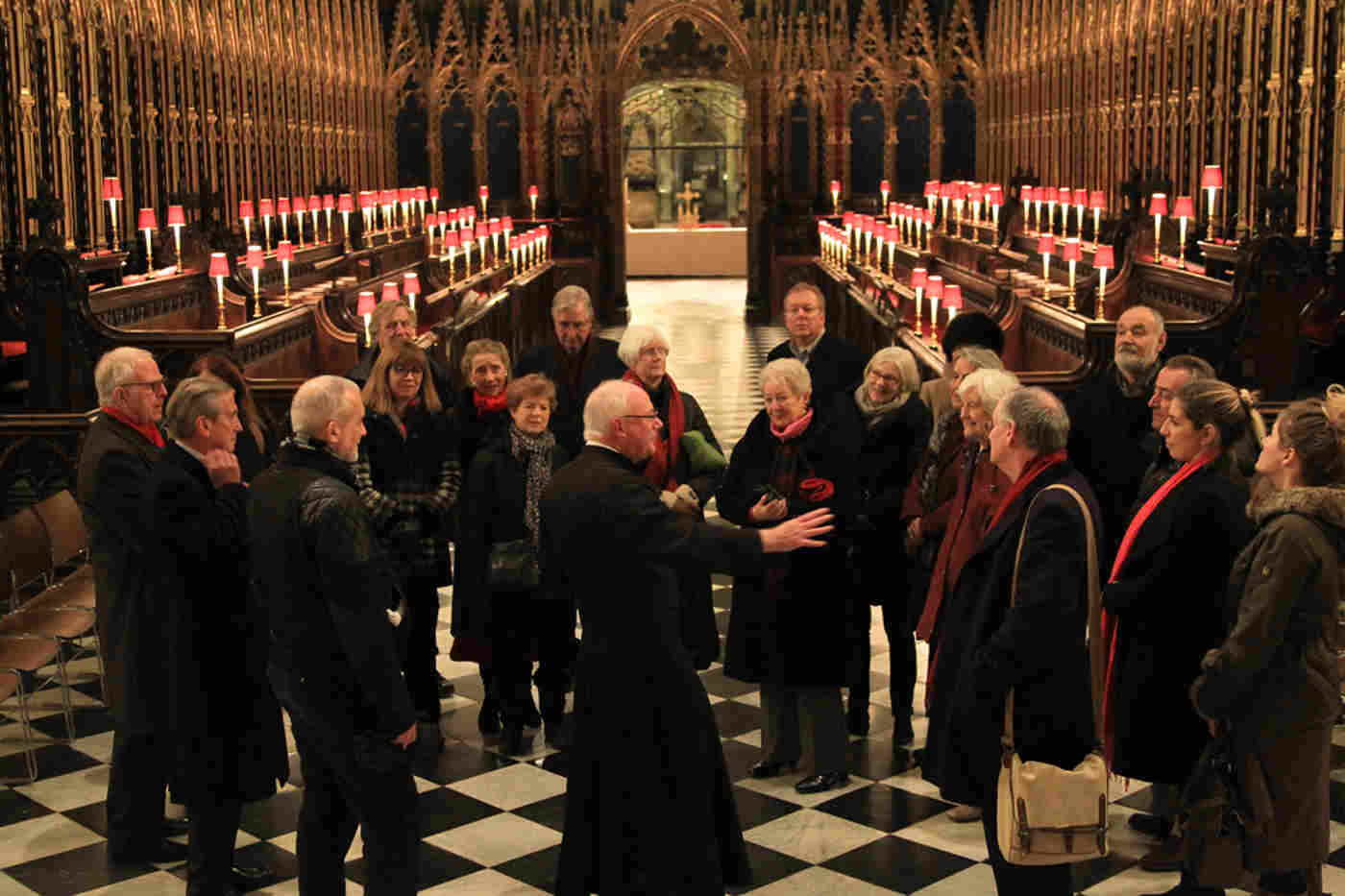 A verger leads a tour group of about 20 people through the Quire of Westminster Abbey