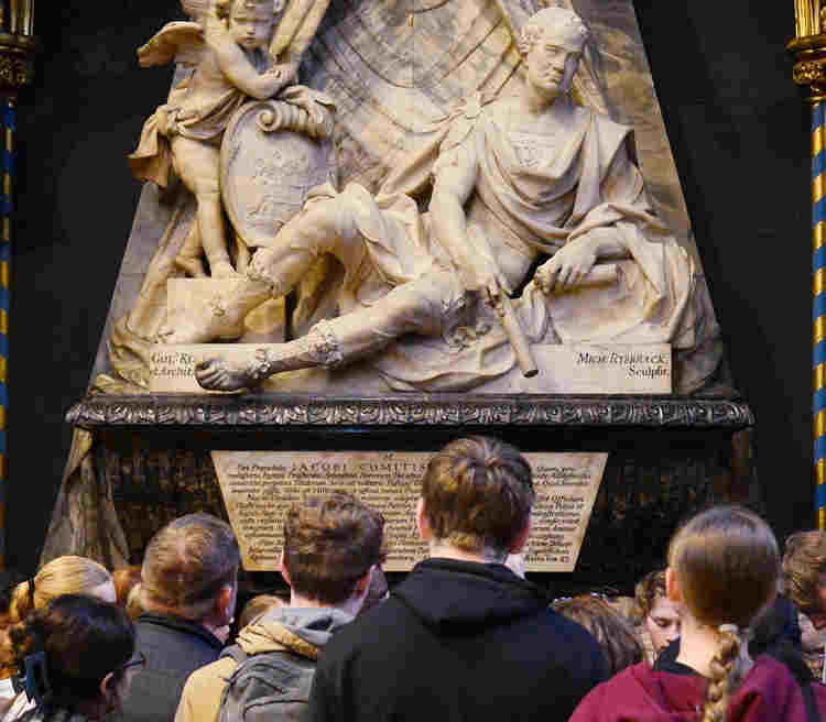 Photo of the Newton memorial in Westminster Abbey with the backs of a group of visitors looking at it