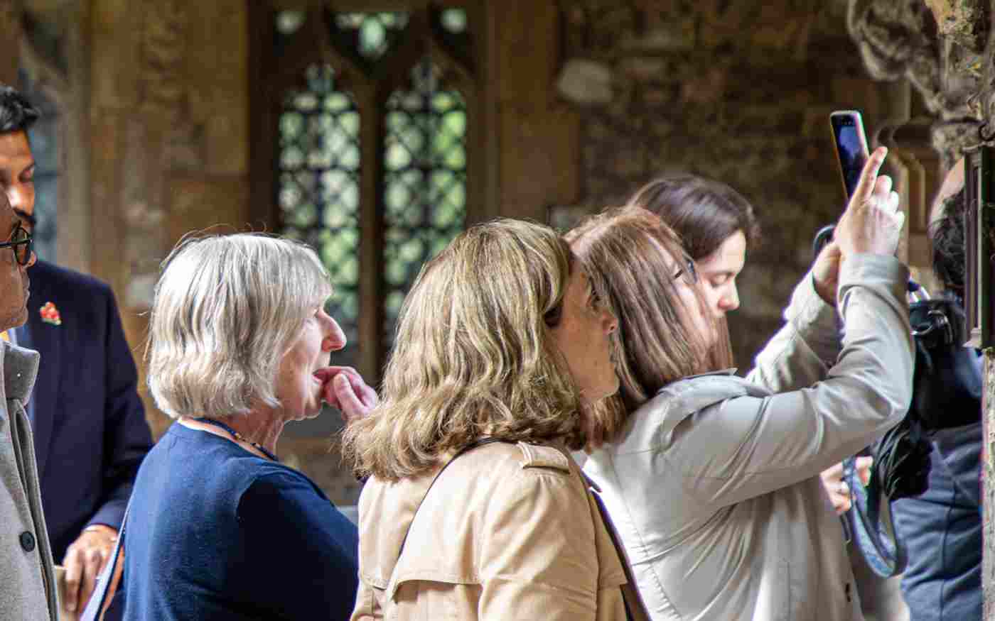 Photograph of people on a tour group looking and taking photographs near a stone wall in Westminster Abbey