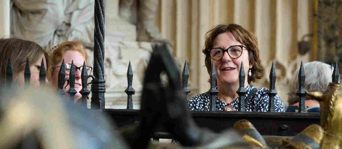 Photograph of member of the public looking over the railings at a memorial within Westminster Abbey
