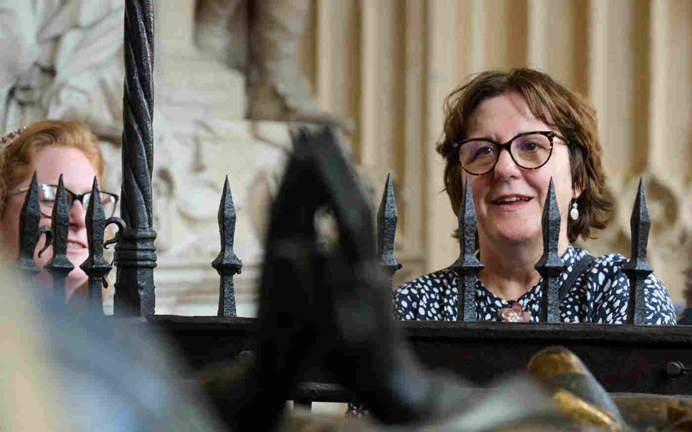 Photograph of member of the public looking over the railings at a memorial within Westminster Abbey