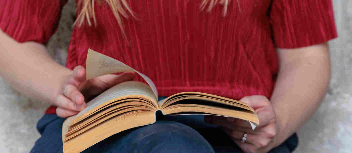 Close-up photograph of woman holding a book and turning the pages