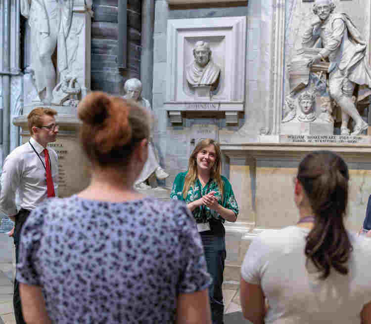 Photograph of a group of adults listening and looking at one adult who is talking within Poets' Corner in Westminster Abbey, representing Teacher CPD and INSET