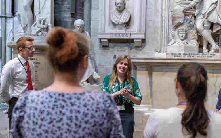 Photograph of a group of adults listening and looking at one adult who is talking within Poets' Corner in Westminster Abbey, representing Teacher CPD and INSET