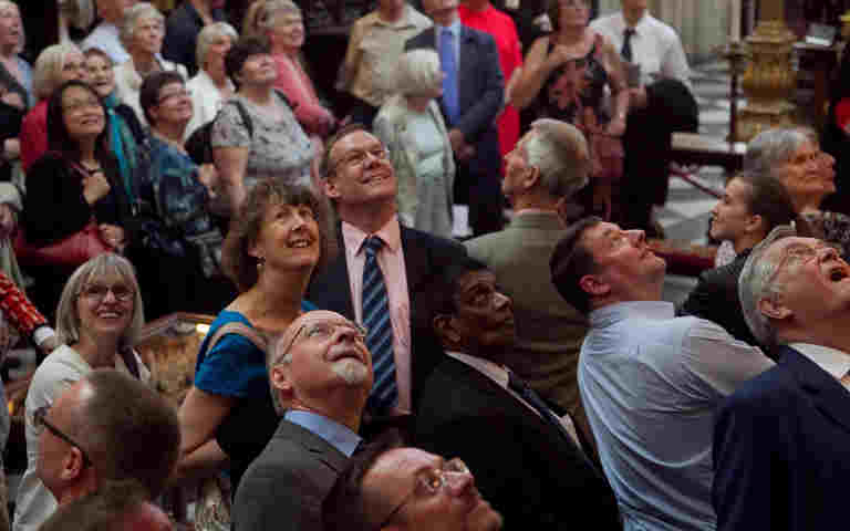 Photograph of a group of adults looking up in different directions in Westminster Abbey