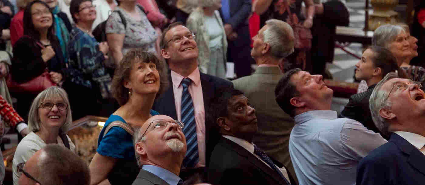 Photograph of a group of adults looking up in different directions in Westminster Abbey
