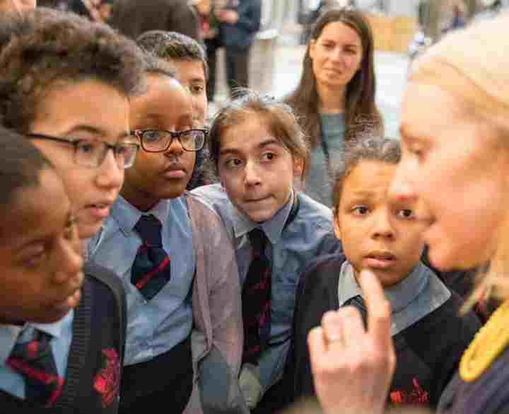 A group of primary school students huddle around a guide during a tour of Westminster Abbey